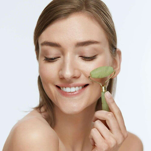 Femme souriante utilisant un rouleau de jade visage vert pour massage et soin du visage