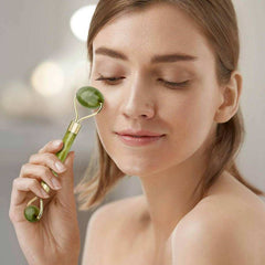 Femme utilisant un rouleau de jade visage vert pour masser et revitaliser sa peau